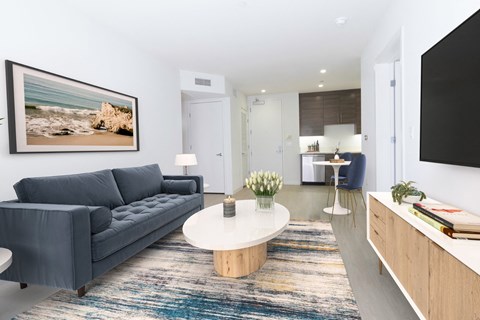 A modern living room with a grey sofa, a coffee table, and a painting on the wall.
