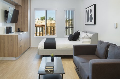 A modern bedroom with a large bed and a balcony overlooking a cityscape.