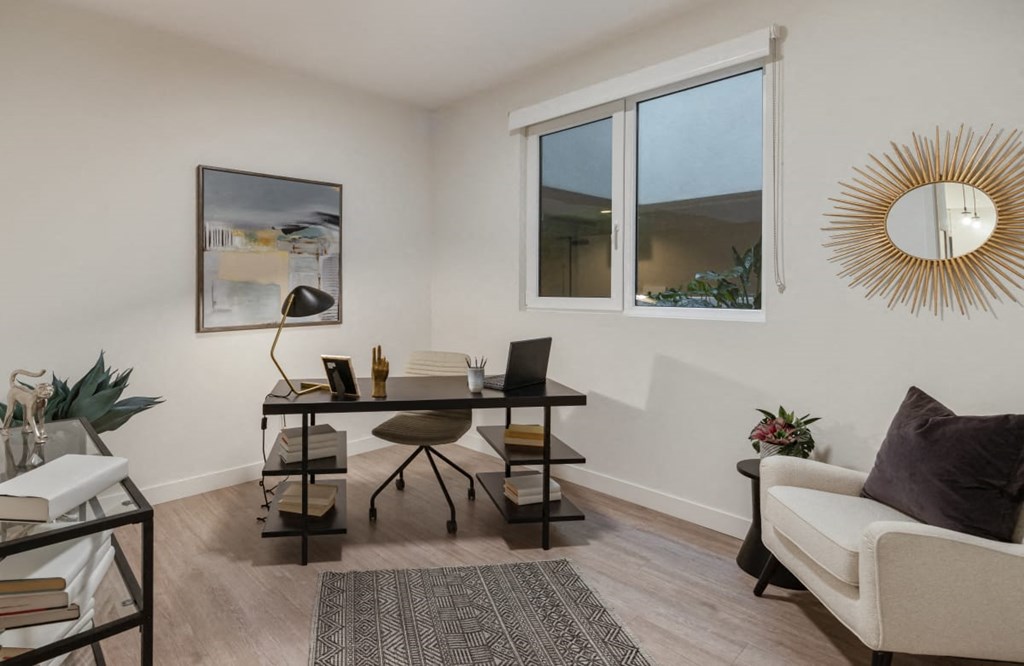 a living room with a couch and a desk with a laptop
