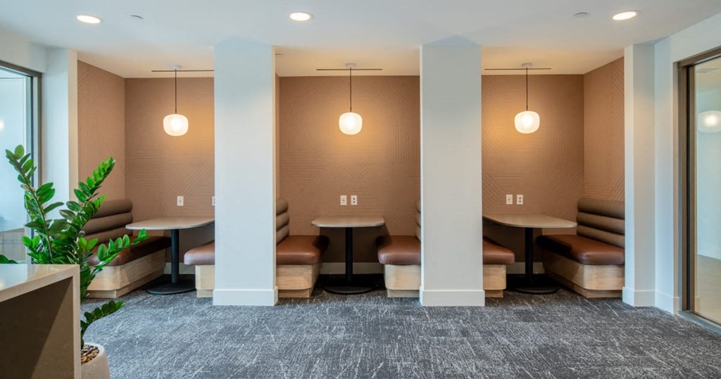 a lounge area with tables and chairs in a room