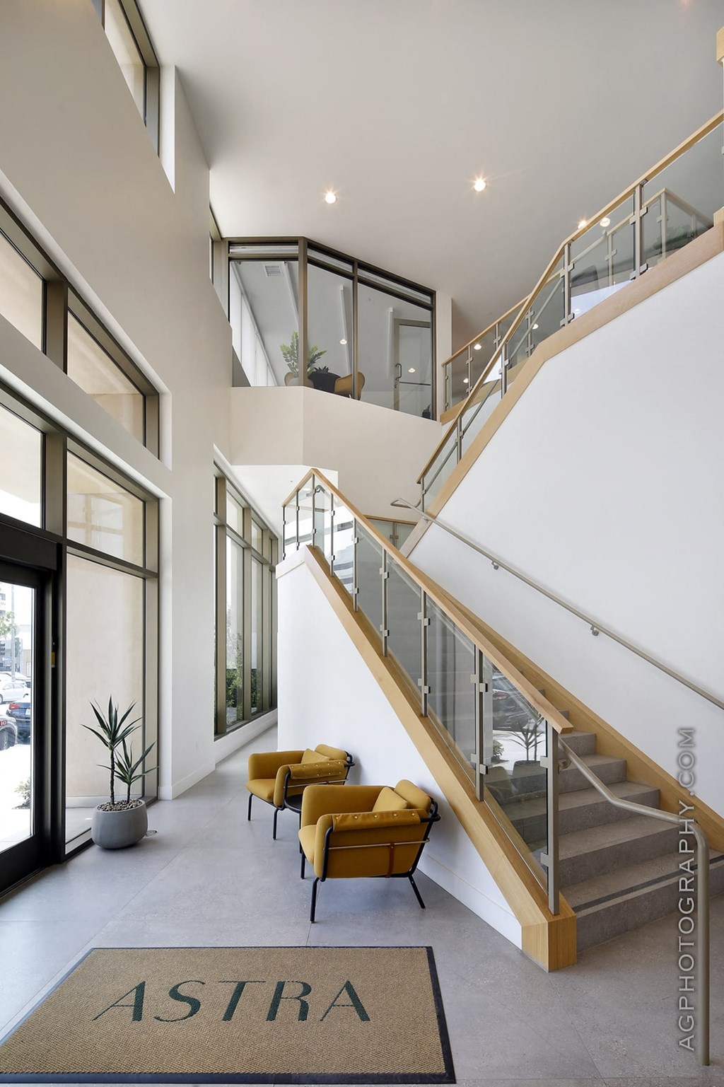a staircase in the middle of a lobby with yellow chairs
