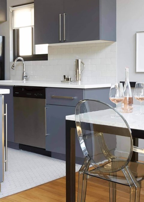 A modern kitchen with a glass table and a chair.