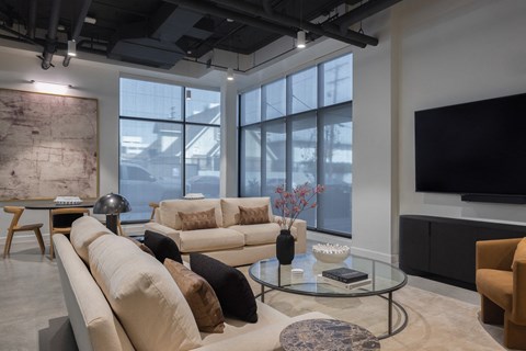 A living room with a large window, a couch, a coffee table, and a television at Skylar At Sunset Apartments, Los Angeles