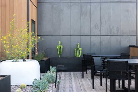 A modern outdoor dining area with a wooden table and chairs at Skylar At Sunset Apartments, Los Angeles, CA