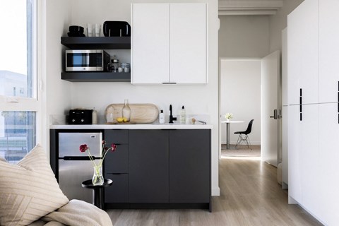 A modern kitchen with white cabinets and a black fridge.