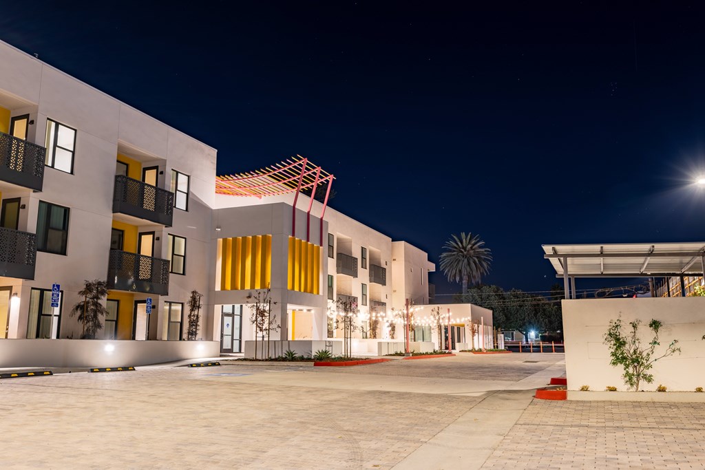 A modern building with yellow and white exterior is illuminated at night.