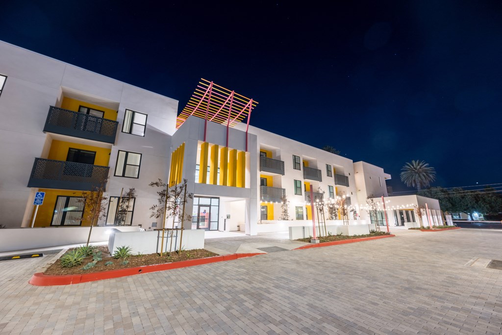 A modern building with yellow and white accents is illuminated at night.