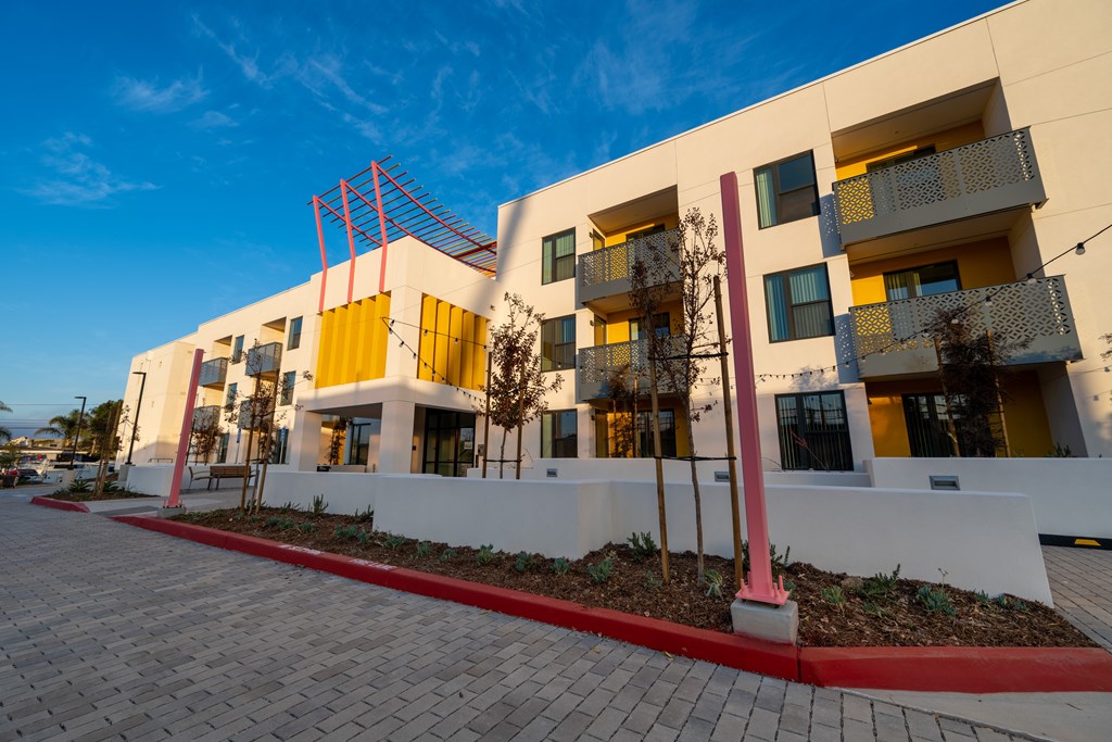 A modern building with a red and yellow facade and balconies.