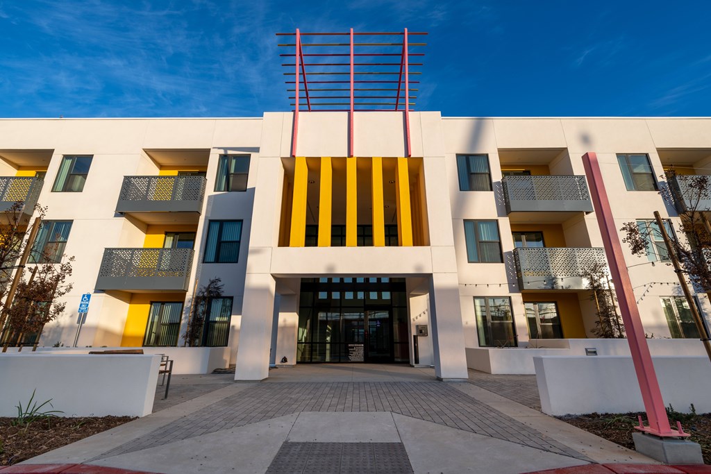A modern building with a white facade and a yellow and black striped entrance.