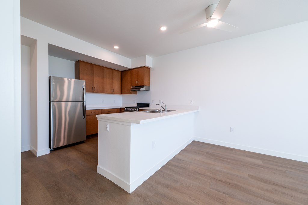 A kitchen with a stainless steel refrigerator and wooden cabinets.