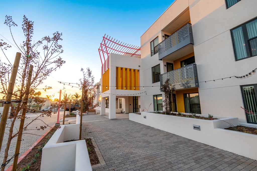A modern building with a white and yellow facade and a red fence.
