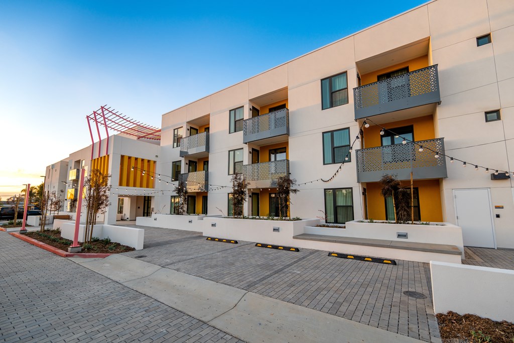 A modern apartment building with balconies and a red sculpture in front.
