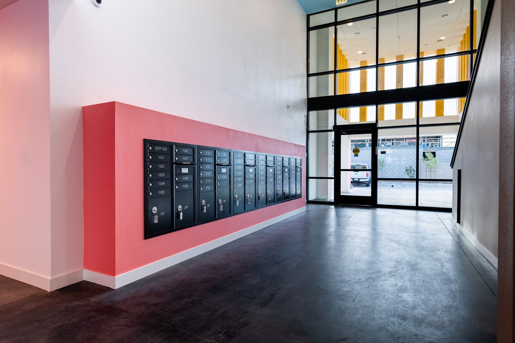 A hallway with a red wall and black and white lockers.