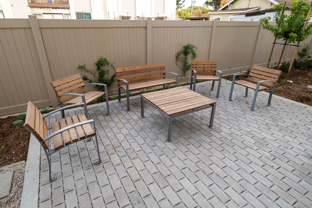 A set of four wooden chairs and a table are arranged on a patio.