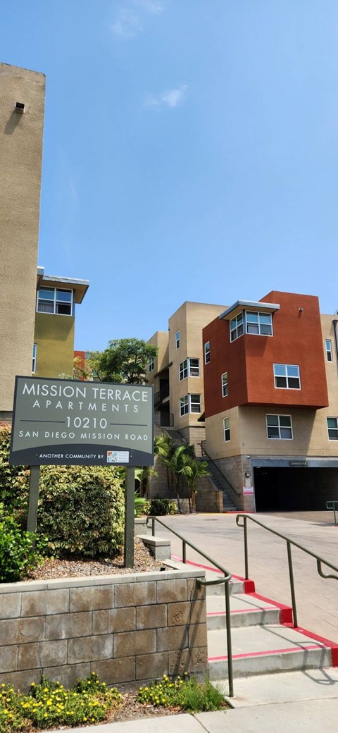 A sign for Mission Terrace Apartments stands in front of a building.