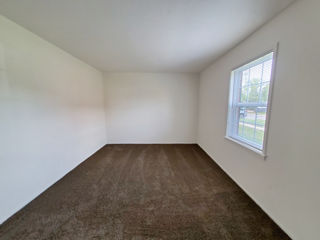 Bedroom in a 1 bedroom apartment with carpet and a window at Carriage House West.