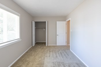 Second Bedroom with a Closet and Large Windows in the Two Bedroom Townhome at Woodbridge Apartments Bloomington - Photo Gallery 43