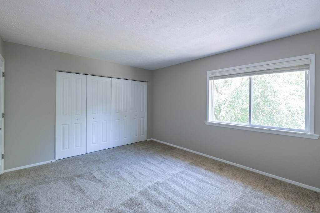 Primary Bedroom with a Closet and Large Windows in the Two Bedroom Townhome at Woodbridge Apartments Bloomington