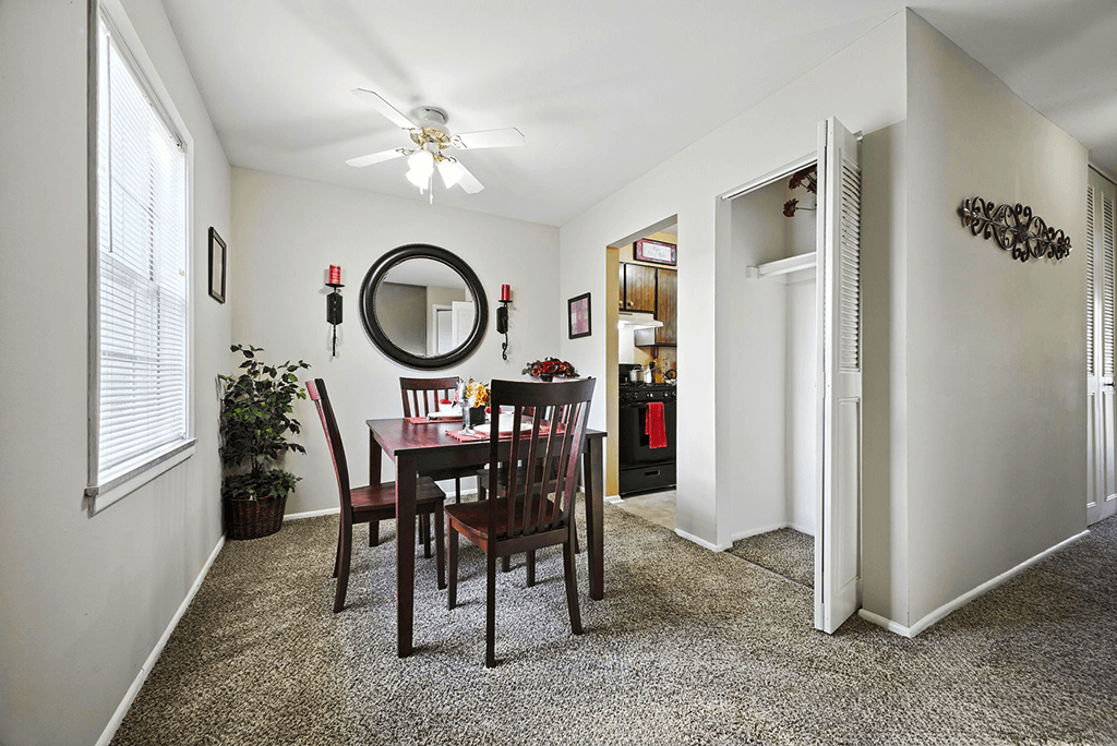 Dining area in a 2-bedroom Ashton Pointe apartment with a carpeted floor and natural light from windows.