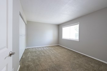 Primary Bedroom with a Large Window in the Three Bedroom Townhome at Woodbridge Apartments Bloomington - Photo Gallery 35