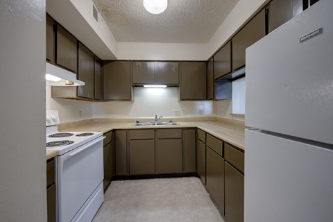 A kitchen with brown cabinets and a white refrigerator.