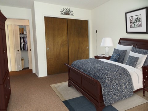 A bedroom with a bed, nightstand, and wardrobe.