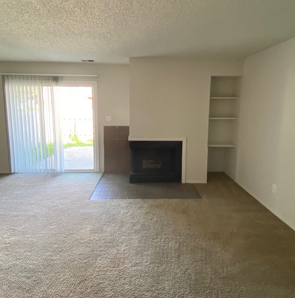 Townhome living room at Ashley Pointe Apartments with a fireplace and a sliding door to patio