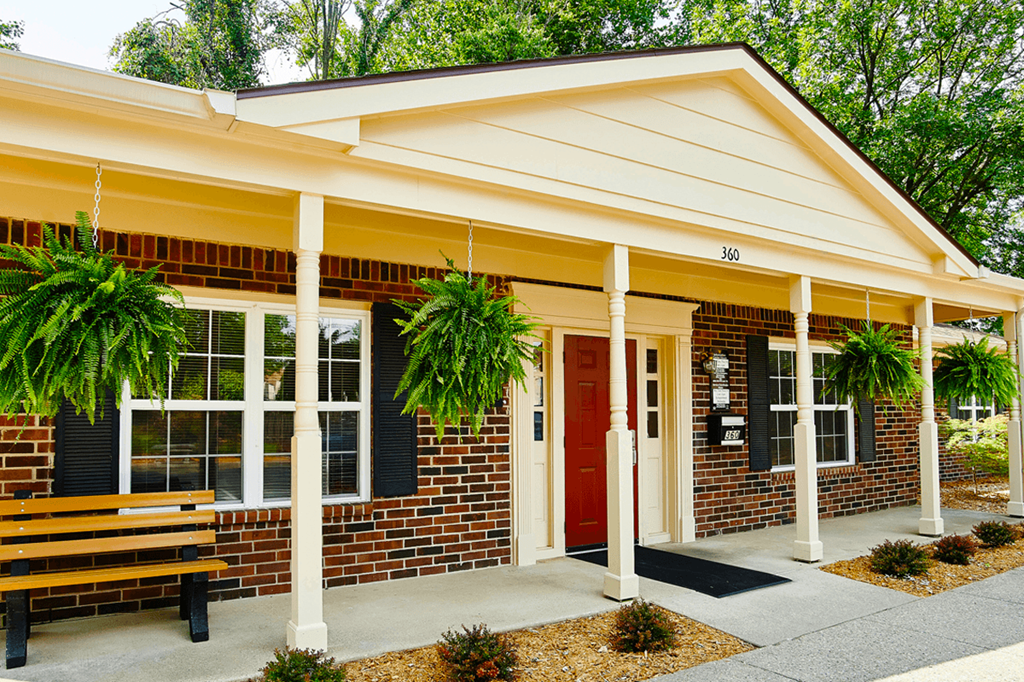 A small building with a red door and a bench in front.