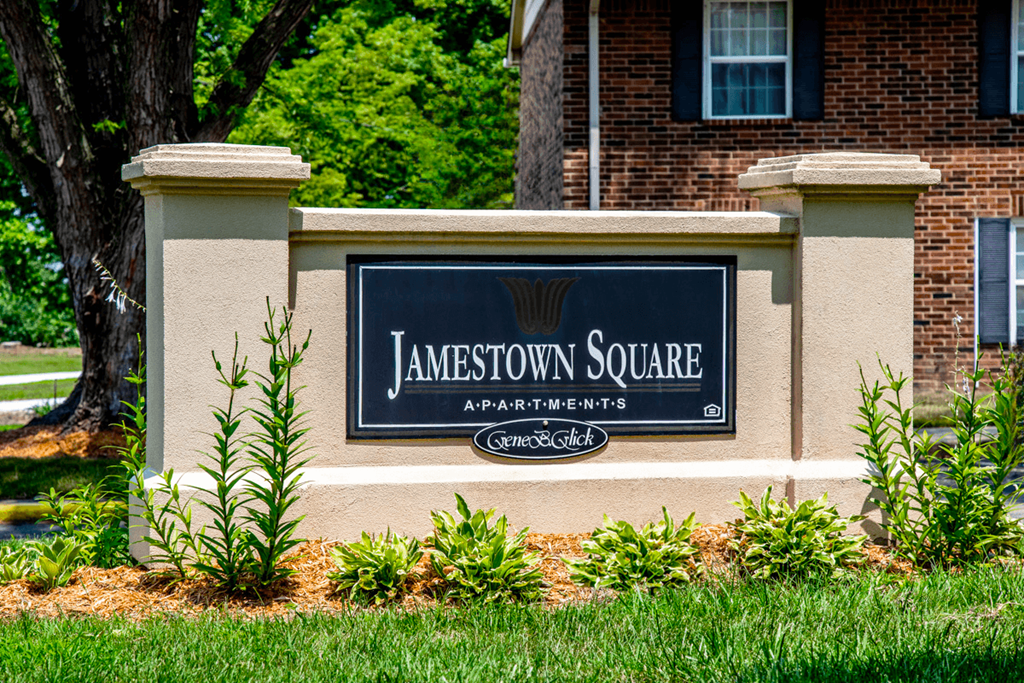 A sign that says Jamestown Square in front of a brick building.