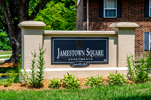 A sign that says Jamestown Square in front of a brick building.