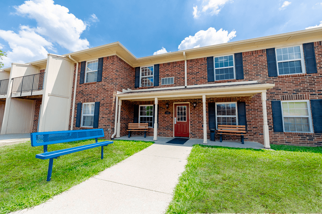 A blue bench sits in front of a brick building.