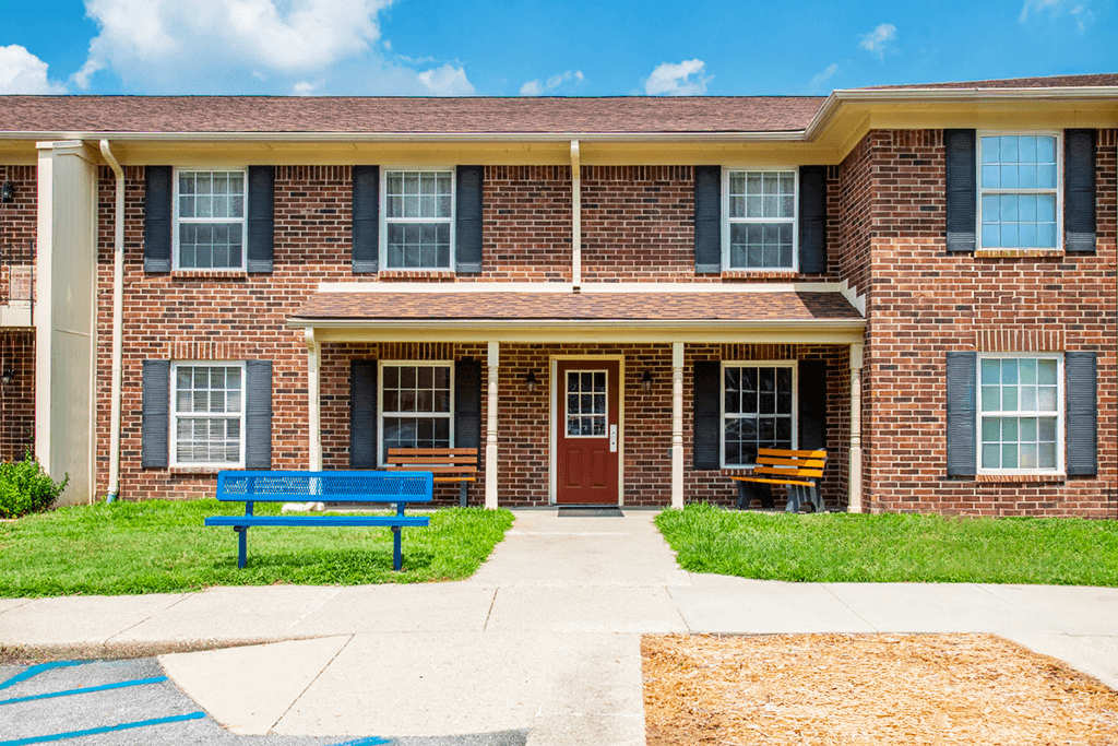 A brick building with a blue bench in front.