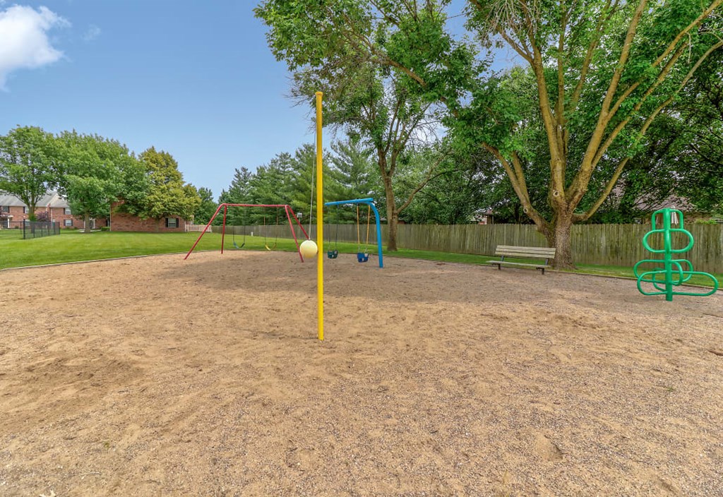 Playground at Ashley Pointe Apartments with swing sets, tetherball and climbing equipment
