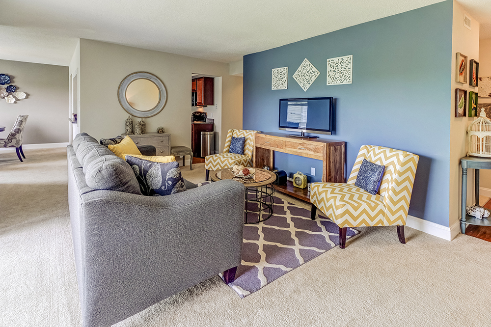 A living room with a grey couch and a yellow and white chair.