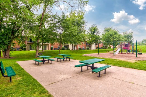 A park with green benches and a playground.