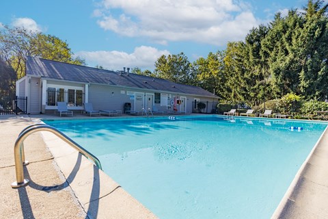 Outdoor swimming pool with poolhouse and lounge chairs at Woodbridge of Bloomington Apartments, Bloomington, 47408