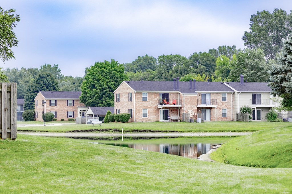 a pond in front of a row of brick apartment buildings