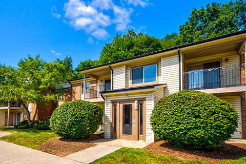 Exterior view of an apartment building at Woodland Crossing, featuring balconies and patios on upper and lower levels.