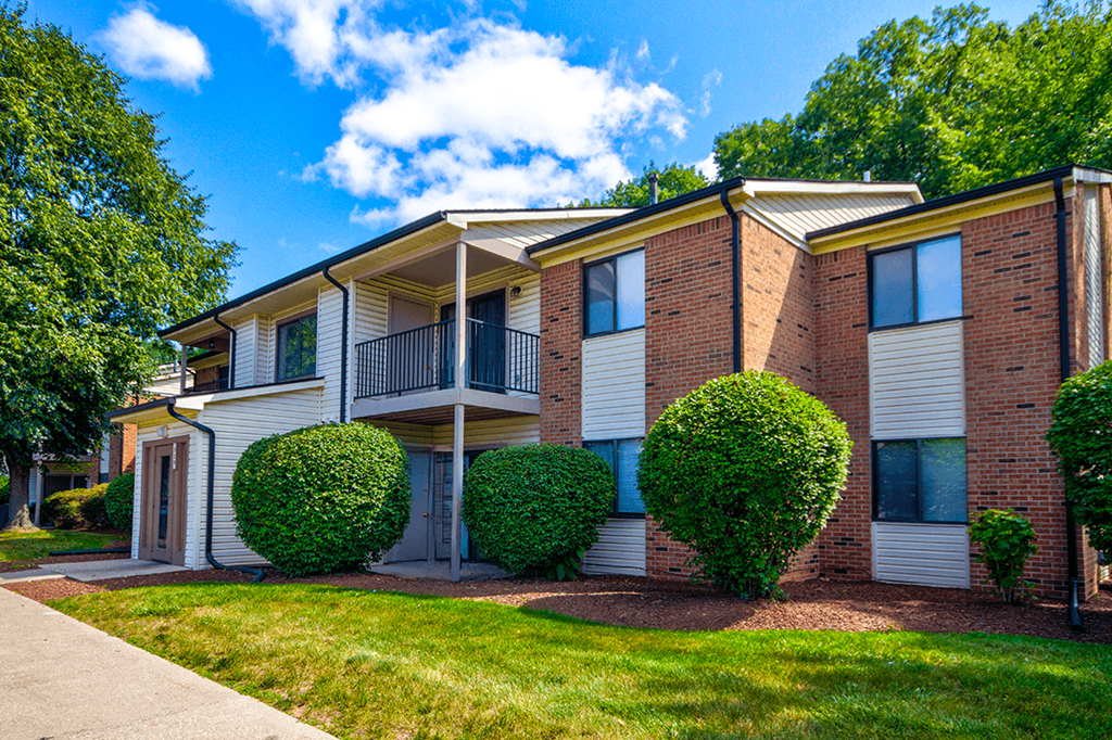 Exterior view of an apartment building at Woodland Crossing, featuring balconies and patios on upper and lower levels.