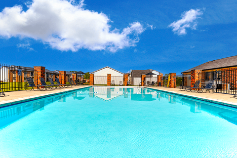 Outdoor pool at Thompson Village Apartments, surrounded by lounge chairs.