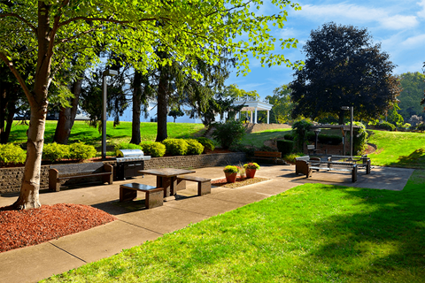BBQ and picnic area featuring benches, a grill, and trees at Kentwood Square Apartments.