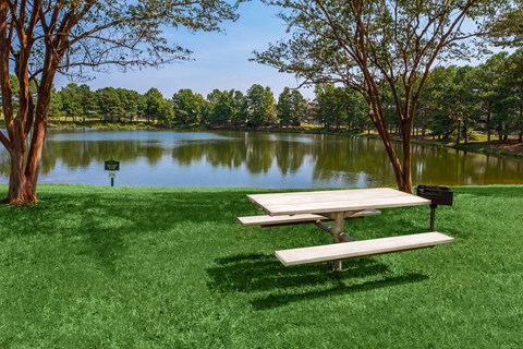 Apartment community amenities Barbeque and picnic area near a pond at King’s Landing Apartments.