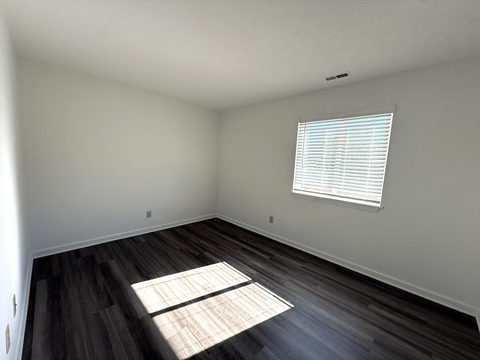 A room with a window and wooden floors.