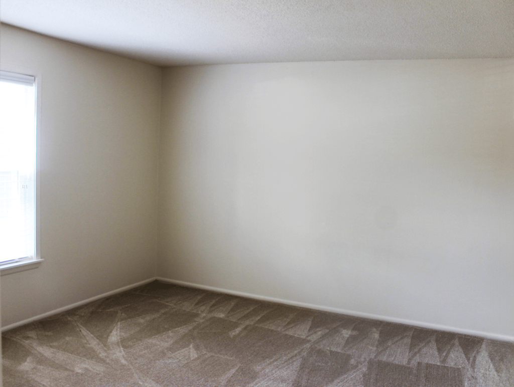 Carpeted bedroom with a window at Cambridge Square Apartments Fort Wayne.