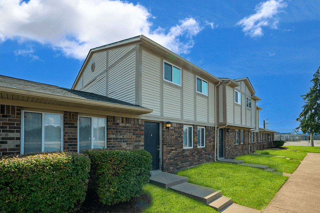 Exterior view of a building at Colonial Village Apartments, showcasing well-maintained landscaping and a classic design.