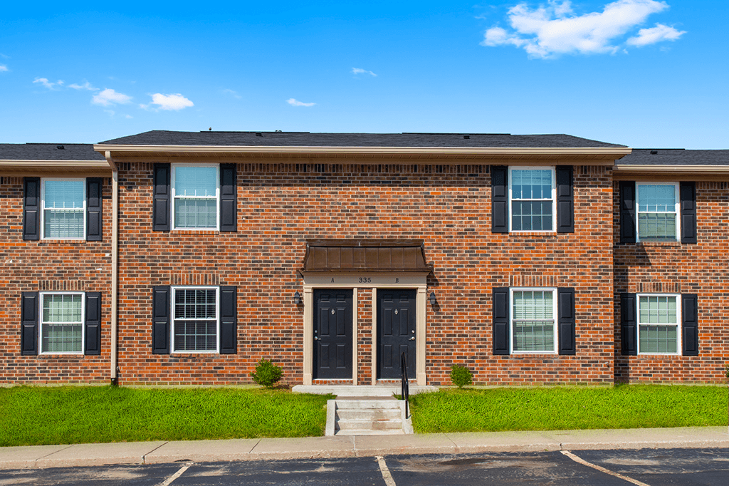 Exterior view of a building with a parking lot in front at Carriage House Apartments in Kendallville.
