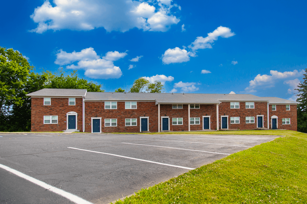 Exterior view of Country View Apartments, showcasing a charming building design with a parking lot in front, surrounded by landscaped greenery.