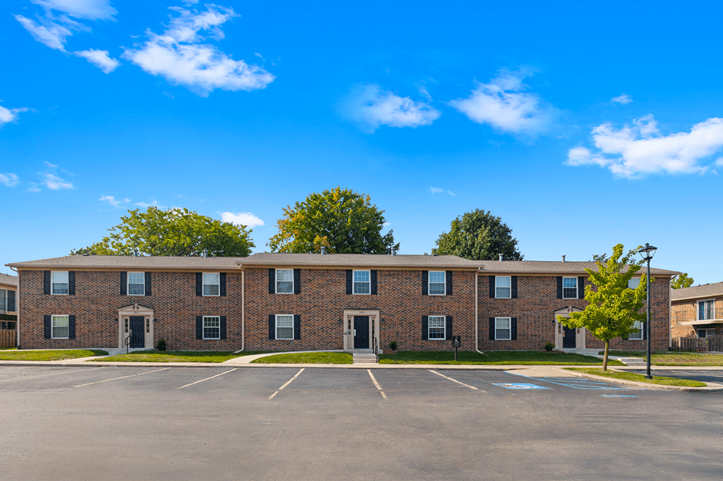 Exterior view of a building with a parking lot in front at Carriage House Apartments in Kendallville.