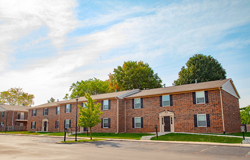 Exterior view of a building with a parking lot in front at Carriage House Apartments in Kendallville.