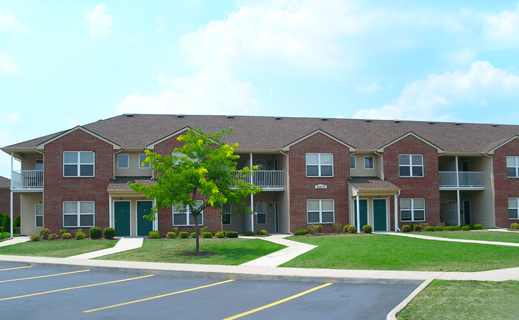 Exterior view of North Lake Apartments with parking area and surrounding landscaping.